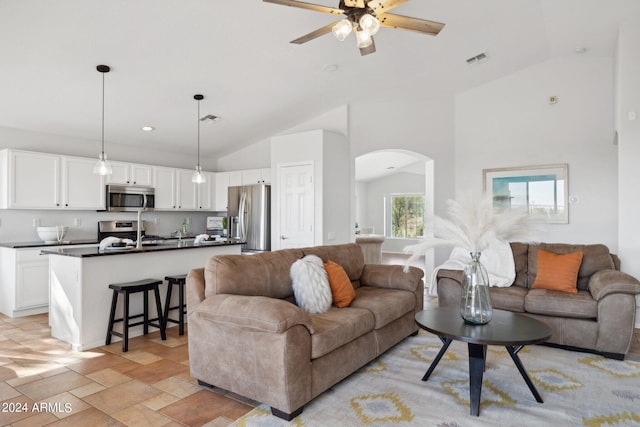 living room featuring arched walkways, ceiling fan, and high vaulted ceiling