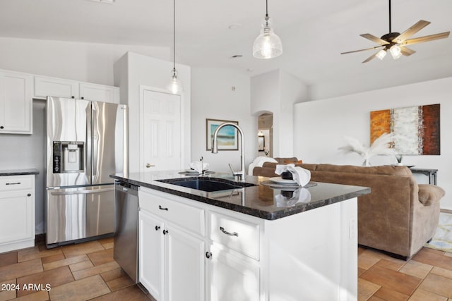 kitchen featuring appliances with stainless steel finishes, a sink, arched walkways, a ceiling fan, and stone finish floors