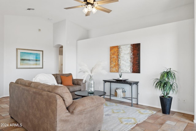 living room with arched walkways, ceiling fan, baseboards, and high vaulted ceiling