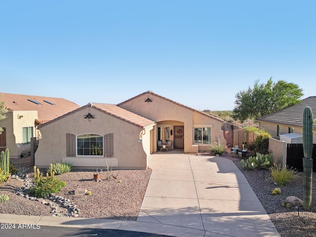 mediterranean / spanish house featuring stucco siding, fence, and a tiled roof