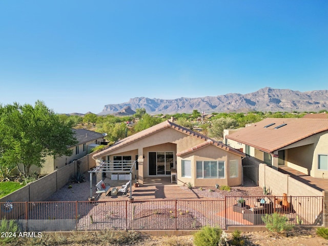 view of front of home with stucco siding, a fenced backyard, a mountain view, and a tile roof