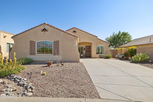 mediterranean / spanish home with stucco siding, fence, a patio, a tiled roof, and driveway