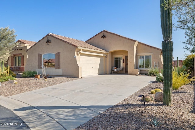 mediterranean / spanish-style home with stucco siding, a tiled roof, an attached garage, and concrete driveway