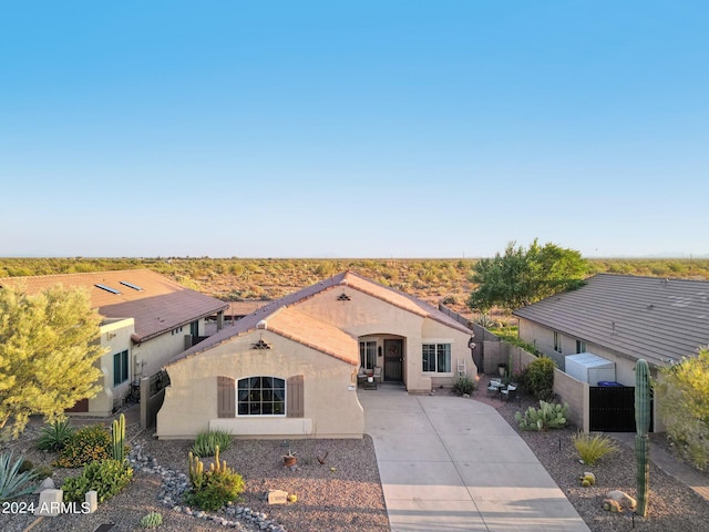 mediterranean / spanish-style home with concrete driveway, stucco siding, a gate, and a tile roof