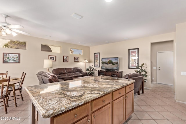 kitchen with light tile patterned floors, light stone countertops, and a center island