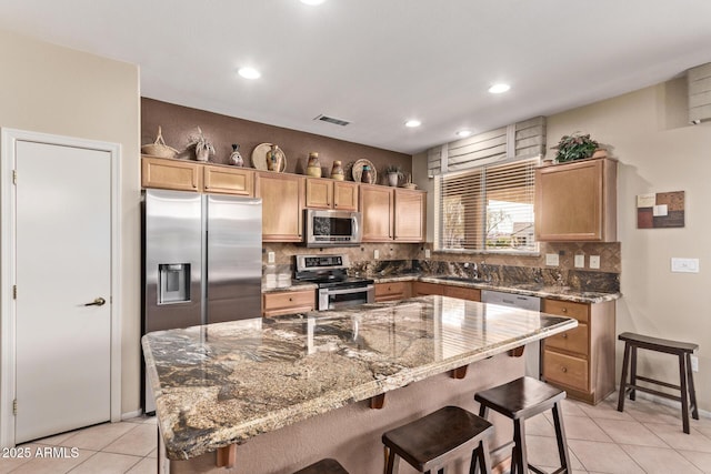 kitchen featuring a kitchen bar, decorative backsplash, a kitchen island, and appliances with stainless steel finishes