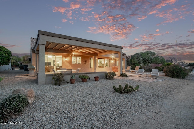 back house at dusk featuring a patio area