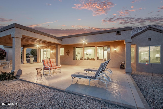 back house at dusk featuring a patio and an outdoor kitchen