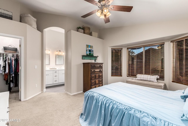 bedroom with a spacious closet, ceiling fan, light carpet, ensuite bath, and a closet