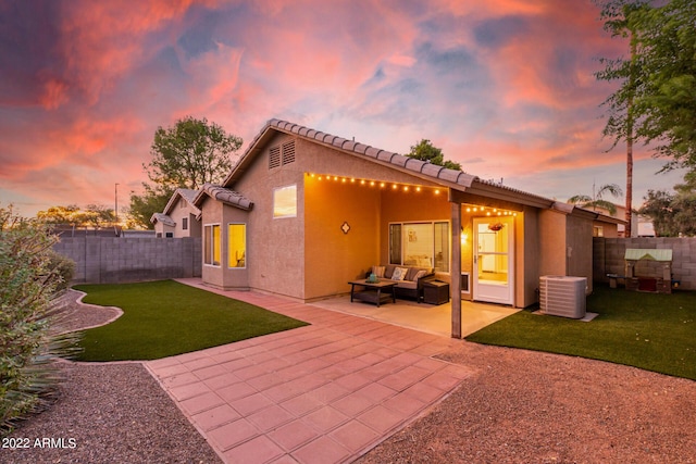 back house at dusk featuring a patio, a yard, an outdoor hangout area, and central air condition unit