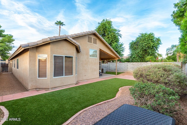 rear view of property featuring a yard, a patio area, and central air condition unit