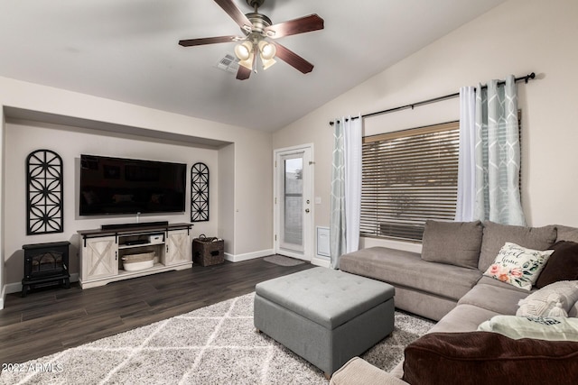 living room featuring ceiling fan, dark hardwood / wood-style floors, vaulted ceiling, and a wood stove