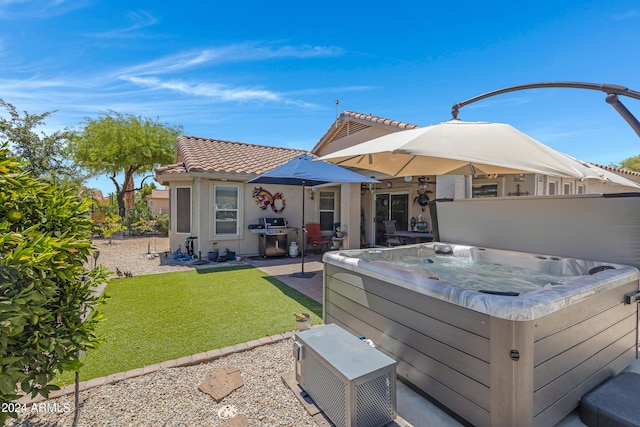 rear view of house featuring a lawn, a patio area, and a hot tub