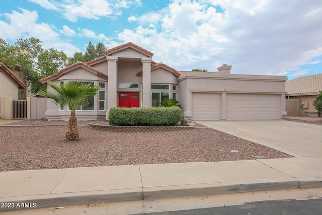 mediterranean / spanish home with a tiled roof, stucco siding, a chimney, driveway, and an attached garage