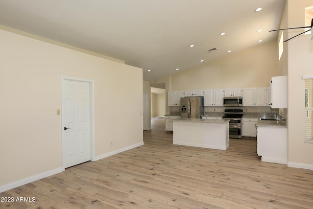 kitchen featuring a center island, stainless steel appliances, white cabinets, light wood finished floors, and baseboards