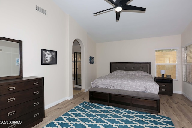 bedroom with visible vents, baseboards, light wood-type flooring, arched walkways, and a ceiling fan