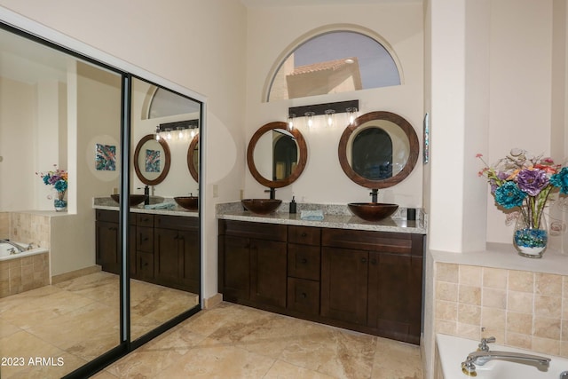 bathroom with a bath, a sink, and double vanity