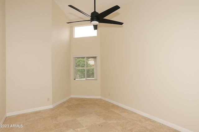 empty room with a ceiling fan, baseboards, and a towering ceiling