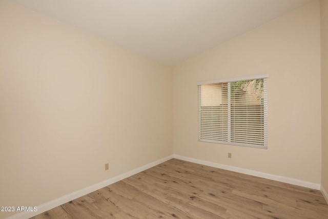 unfurnished room with lofted ceiling, light wood-style floors, and baseboards