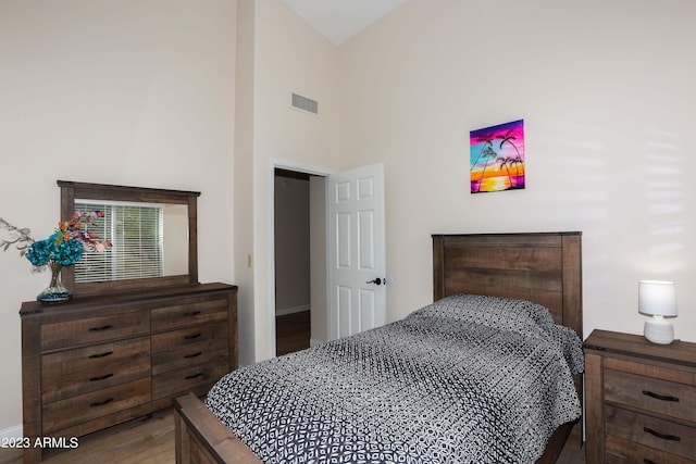 bedroom with visible vents, a towering ceiling, and wood finished floors