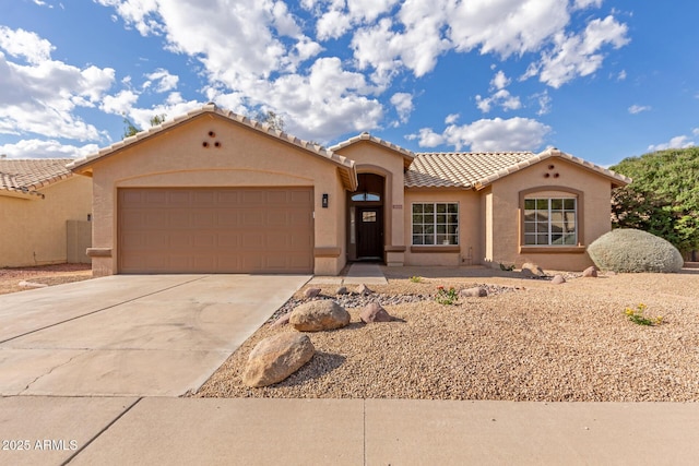 mediterranean / spanish-style home with an attached garage, stucco siding, a tiled roof, and concrete driveway