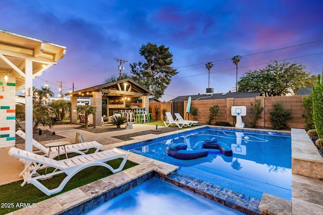 pool at dusk featuring a patio area and exterior bar