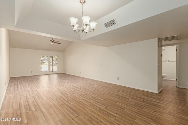 unfurnished living room featuring hardwood / wood-style flooring, vaulted ceiling, and ceiling fan with notable chandelier