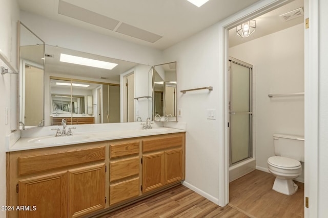 bathroom featuring vanity, hardwood / wood-style floors, a shower with shower door, and toilet