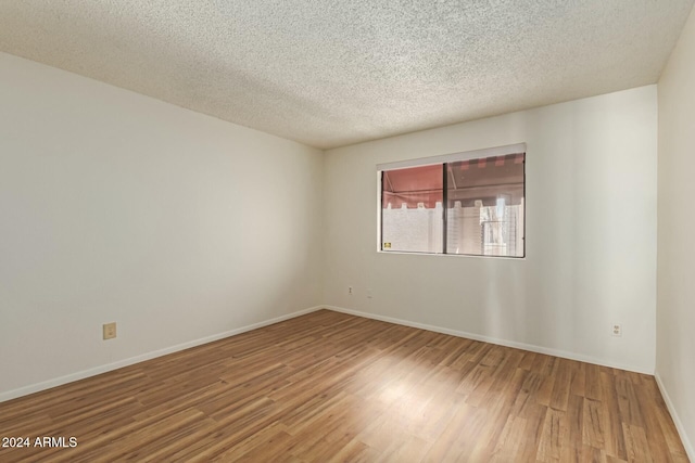 empty room with wood-type flooring and a textured ceiling