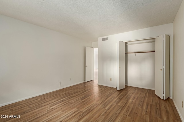 unfurnished bedroom with hardwood / wood-style flooring, a closet, and a textured ceiling