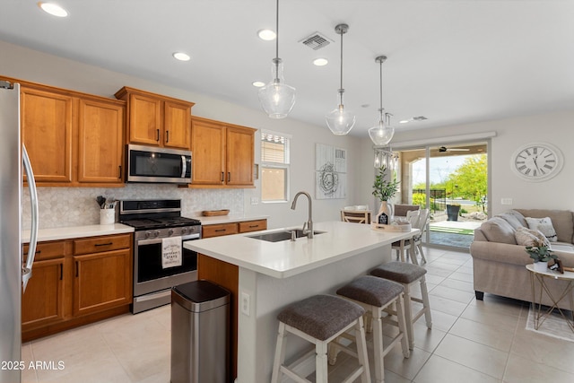 21090 N 267th Dr, Buckeye, AZ 85396 - kitchen featuring brown cabinetry, light tile patterned flooring, open floor plan, a sink, and appliances with stainless steel finishes