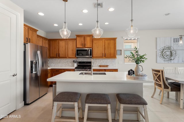21090 N 267th Dr, Buckeye, AZ 85396 - kitchen featuring decorative backsplash, brown cabinetry, visible vents, appliances with stainless steel finishes, and a sink