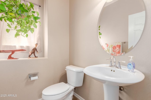bathroom featuring baseboards, toilet, and a sink