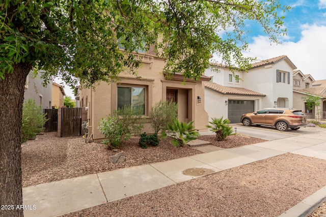 view of front facade with driveway, stucco siding, fence, and an attached garage