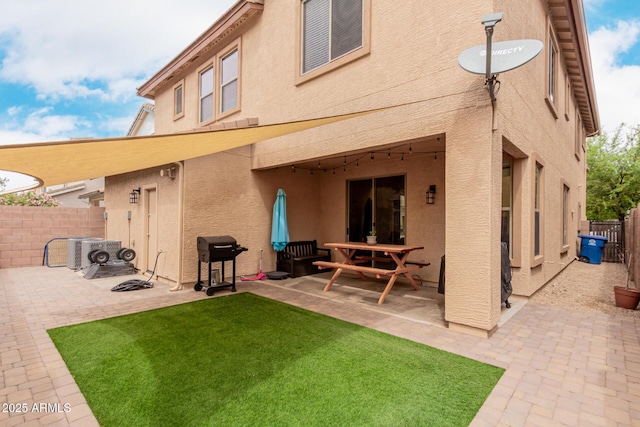 rear view of property with a fenced backyard, stucco siding, a yard, and a patio area