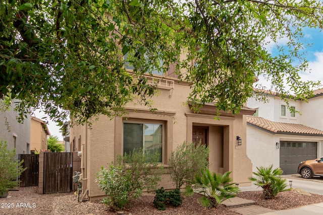 view of front of house with concrete driveway, a gate, stucco siding, and fence