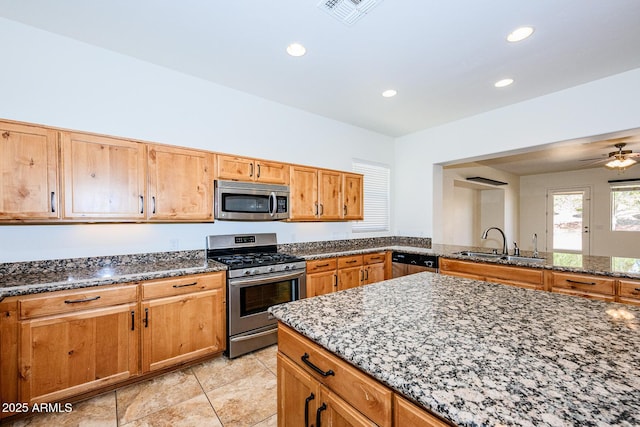 kitchen featuring dark stone counters, a sink, appliances with stainless steel finishes, and visible vents