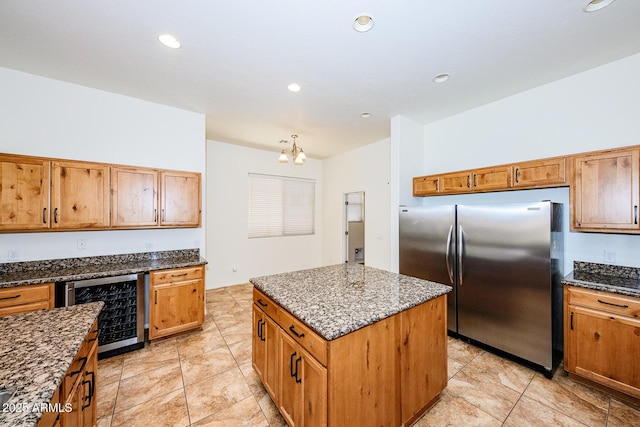 kitchen featuring a chandelier, freestanding refrigerator, a center island, beverage cooler, and dark stone counters