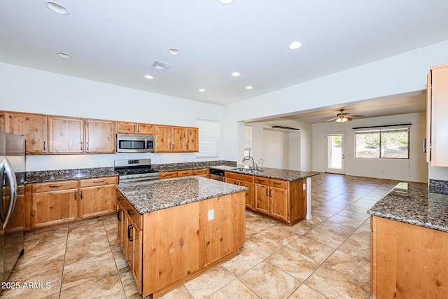 kitchen with dark stone counters, a kitchen island, visible vents, a peninsula, and appliances with stainless steel finishes