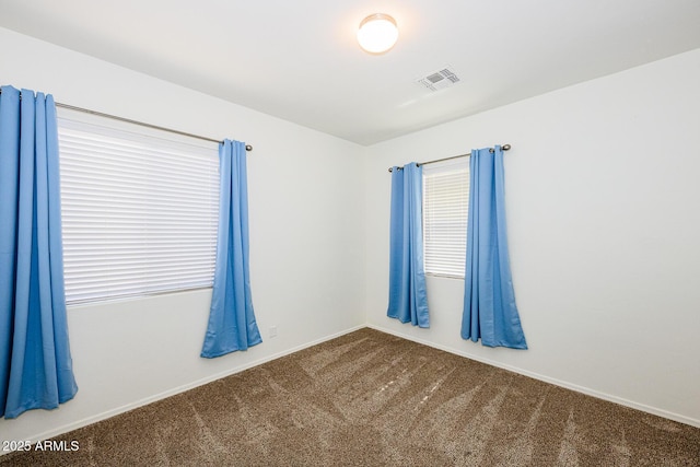 carpeted empty room featuring baseboards and visible vents