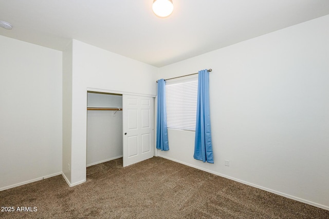 unfurnished bedroom featuring baseboards, carpet floors, and a closet