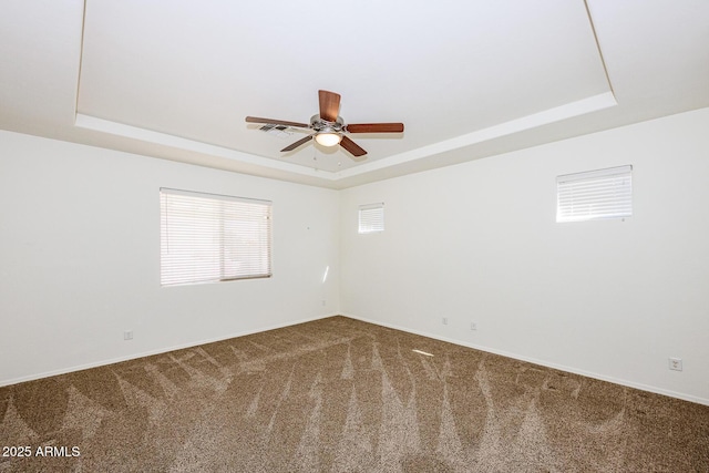 spare room with carpet floors, a tray ceiling, and ceiling fan