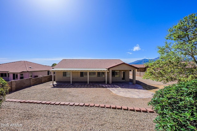 back of property featuring a tile roof, stucco siding, a fenced backyard, a patio, and a mountain view