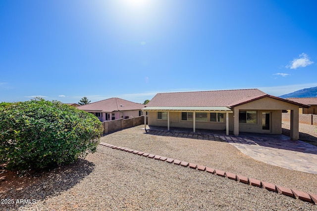 back of property featuring stucco siding, a tile roof, a fenced backyard, and a patio area