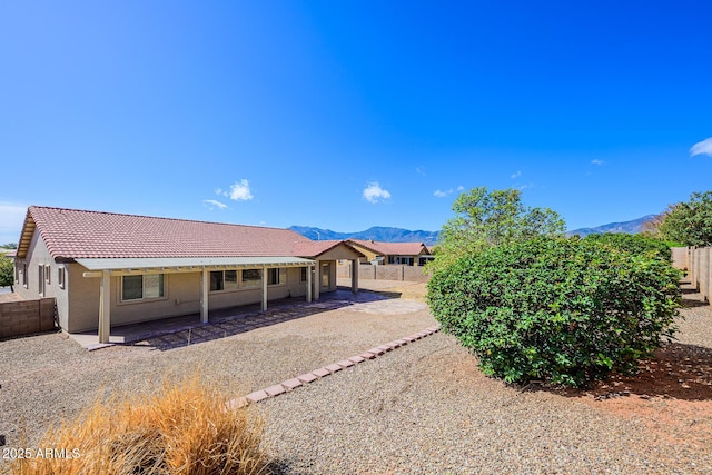 rear view of property featuring a fenced backyard, a tiled roof, stucco siding, and a patio