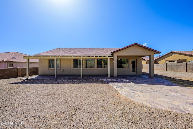 back of house featuring stucco siding, a tiled roof, a patio, and a fenced backyard