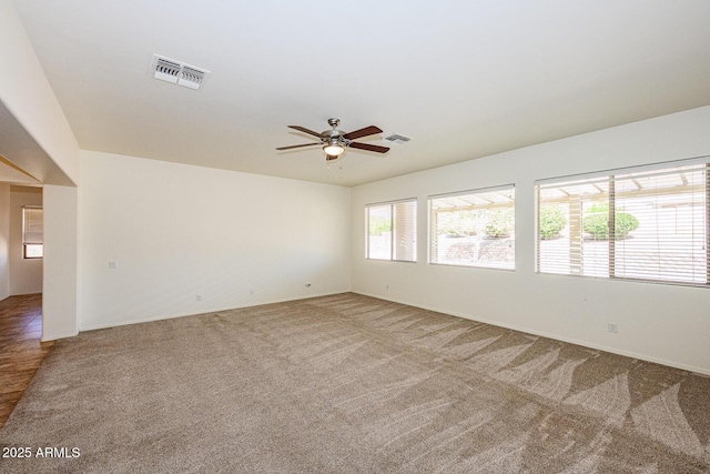 spare room featuring carpet flooring, a ceiling fan, and visible vents