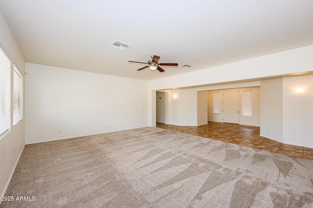 carpeted empty room featuring a ceiling fan and visible vents