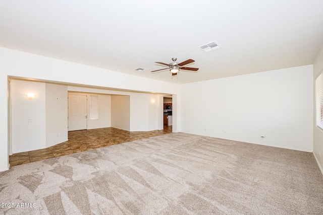 carpeted spare room featuring visible vents and a ceiling fan