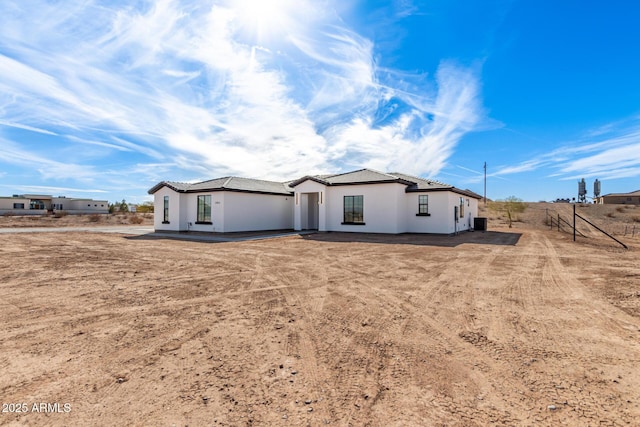 rear view of property featuring a tile roof and stucco siding